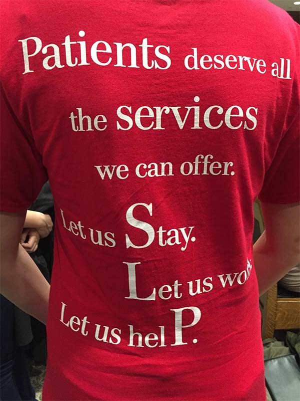 Bill H228 will allow SLP CFYs to stay in Massachusetts to obtain healthcare jobs. Without a provisional licensure, the CFY may leave the state for a healthcare job. "Let us stay; Let us work; Let us help," says the T-shirt.