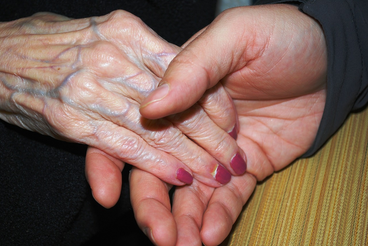 Young therapist holding hands with an elderly woman. Patient safety and compassion!